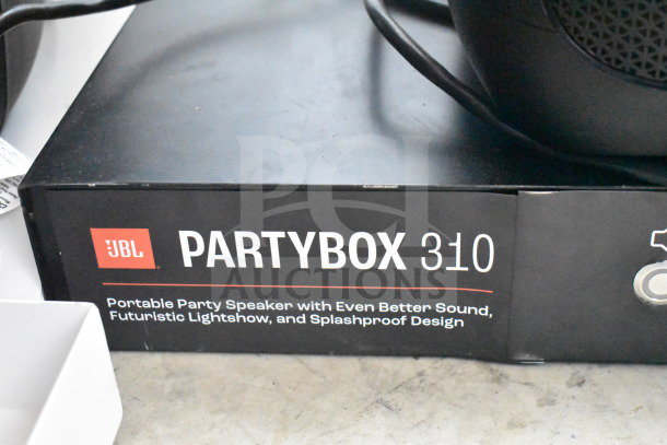 JBL Partybox 310 speaker box with label highlighting portable sound, futuristic lightshow, and splashproof design.