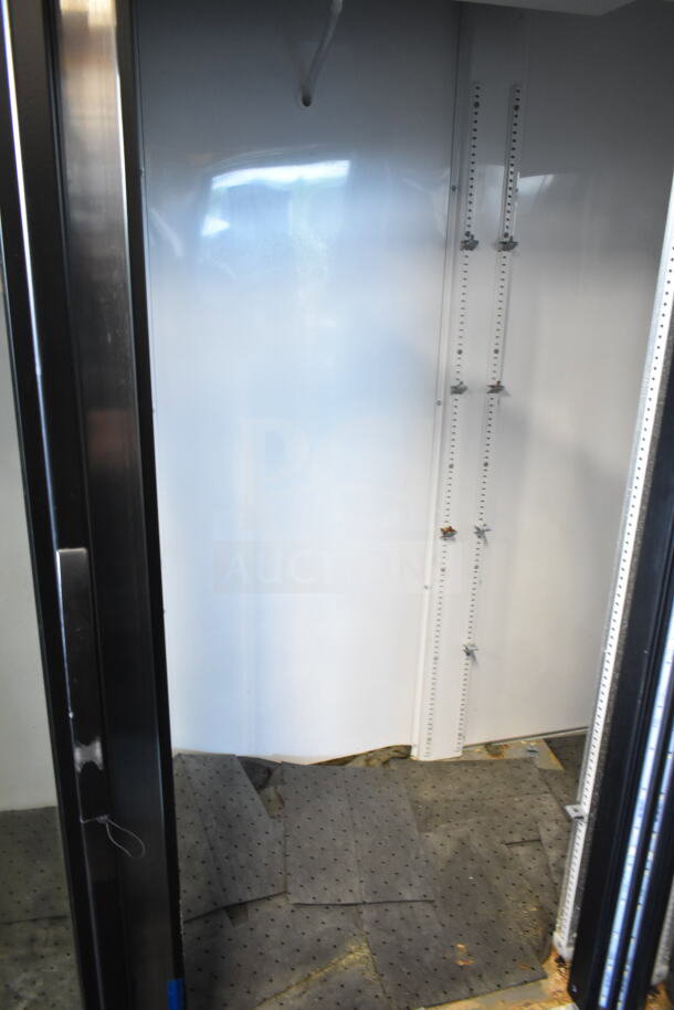 2019 True GDM-72-HC cooler interior, three-door reach-in, white walls, shelf brackets, worn flooring visible.