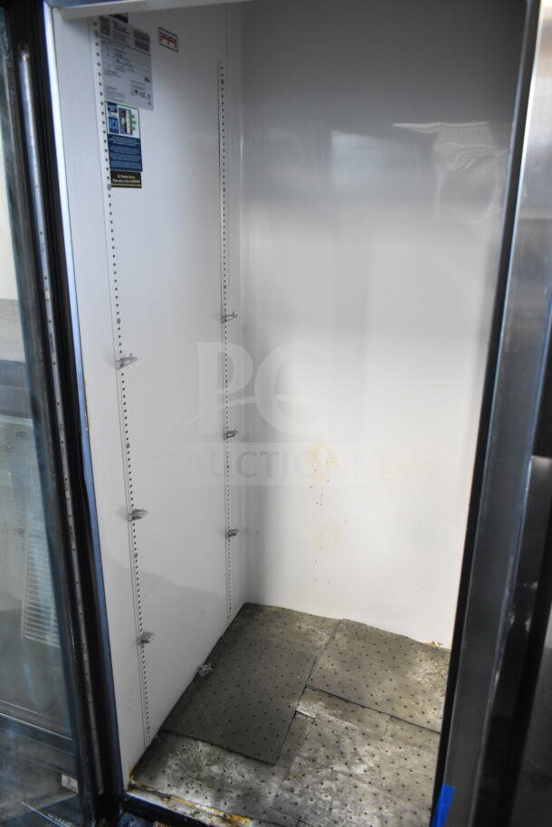 2019 True GDM-72-HC 3 door commercial cooler, 115V, good condition, interior shelving slots, visible wear on interior.
