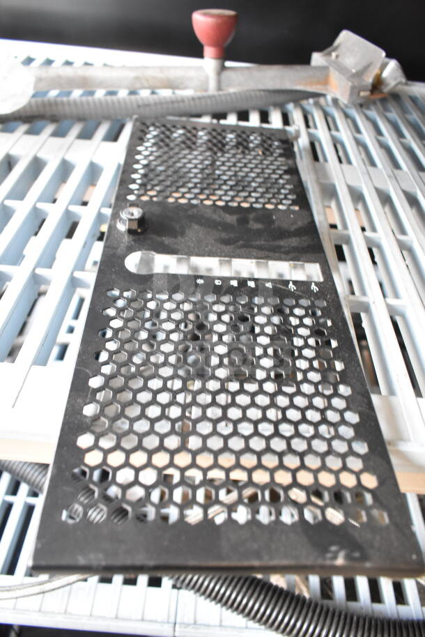 Various industrial and kitchen items including metal grate and red knob on mesh surface. Auction lot includes espresso grinder hopper, slushie machine hopper lid, and dustpan broom.