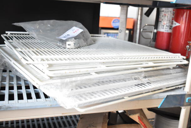 12 assorted items including stacked white racks, wrapped in plastic, on a metal shelf. Auction label on top.