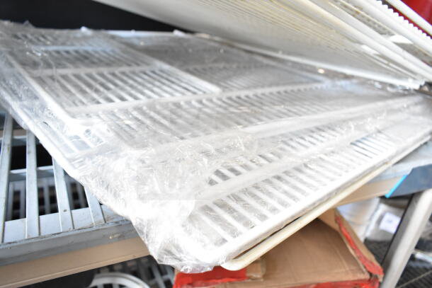 White metal racks, wrapped in plastic, stacked on top of each other. Part of a 12-item auction lot.