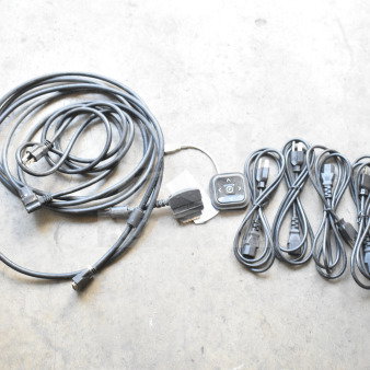 Six various cords, including power and audio cables, bundled on a concrete floor. Features a control pad.