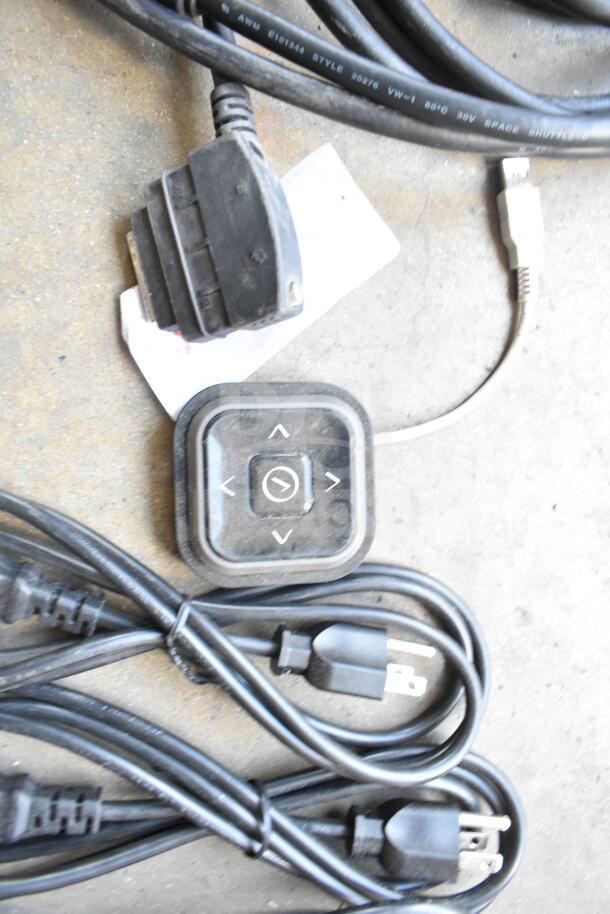 Bundle of assorted cords and a control pad with arrow buttons, used condition. Includes various plug types and connectors.
