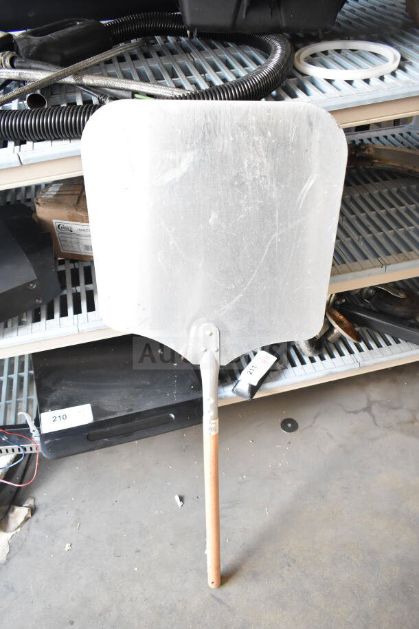 Azzurra pizza peel with metal blade and wooden handle on display. Slight wear visible. Auction includes metal bowls.