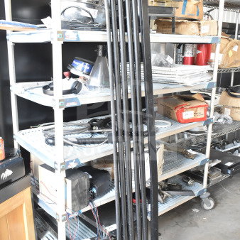 Black metal cooler kickplate, long and vertical, resting against industrial shelving. Appears in good condition.