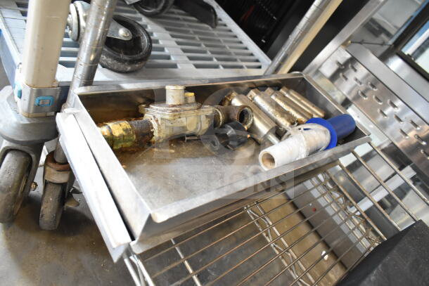 Tray with grease traps, metal pipes, and fittings. Used condition, includes various plumbing components on industrial cart.