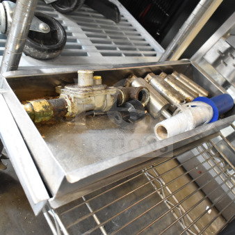 Tray with grease traps, metal pipes, and fittings. Used condition, includes various plumbing components on industrial cart.