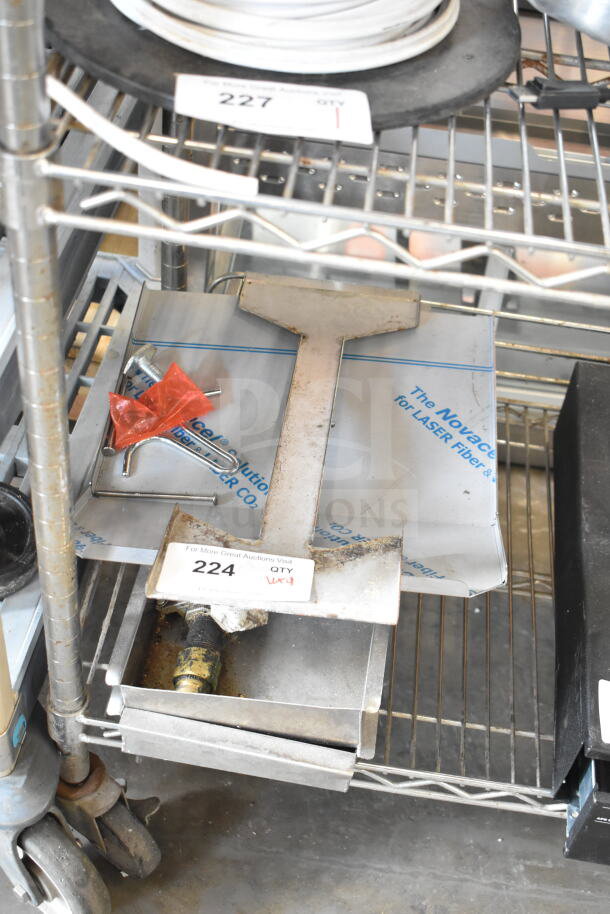 Nine various metal items including grease traps and legs on a metal shelf. Label reads "224 QTY 9X". Good condition.