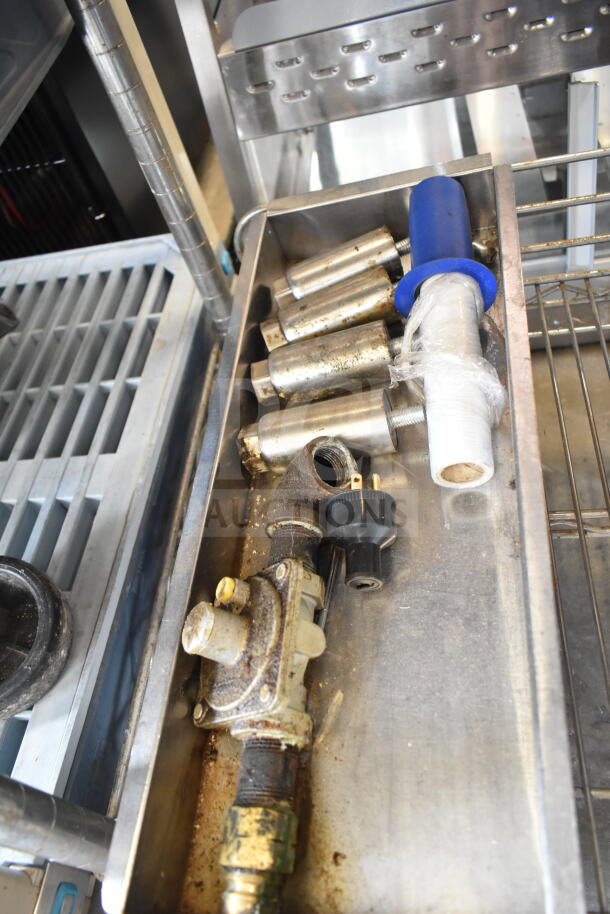 Assorted metal items including grease trap components and legs, shown in a stainless steel tray, various conditions.