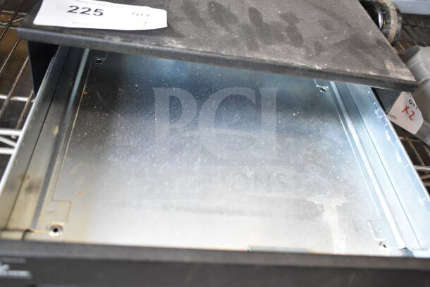 Black countertop cash drawer, open view, shows metal interior, with dust. Tag shows "225 QTY 1." Slight surface wear.