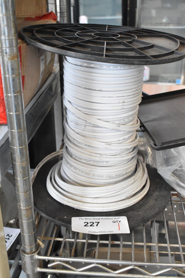 Spool of white cable on a metal rack, marked "SH SIMH" and "PCS25" with auction tag reading "227."