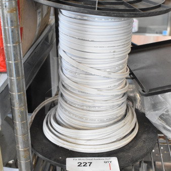 Spool of white cable on a metal rack, marked "SH SIMH" and "PCS25" with auction tag reading "227."