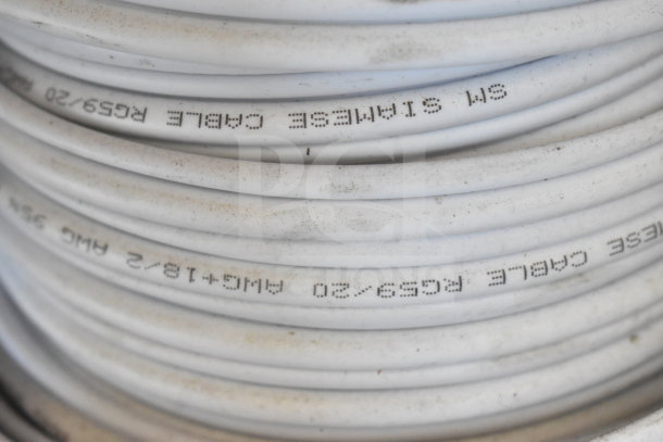 Coiled white cable, marked "RG59/20" and "5M Siamese Cable." Slightly dusty, suitable for electronics or networking.