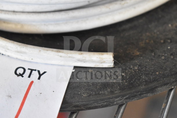 White spool of cable with visible dirt on a black surface. Partial quantity tag shown. Condition appears used.