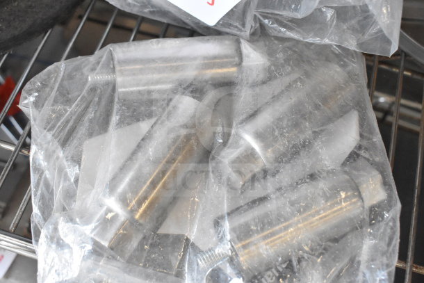 Three metal legs sealed in plastic packaging, part of an auction lot including a brew basket. Condition appears new.