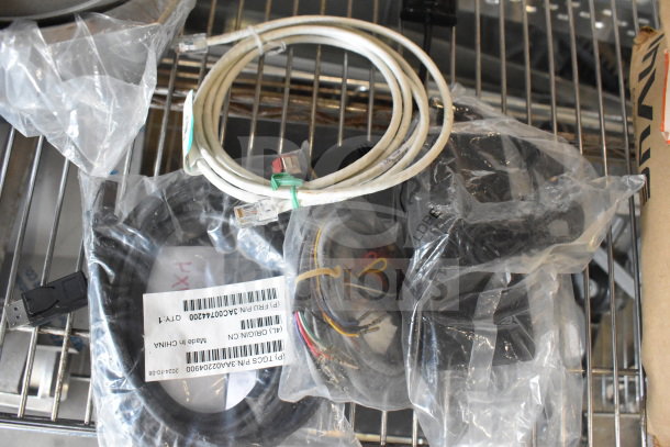 Four various cables, including Ethernet and USB, in plastic bags with labels indicating part numbers.