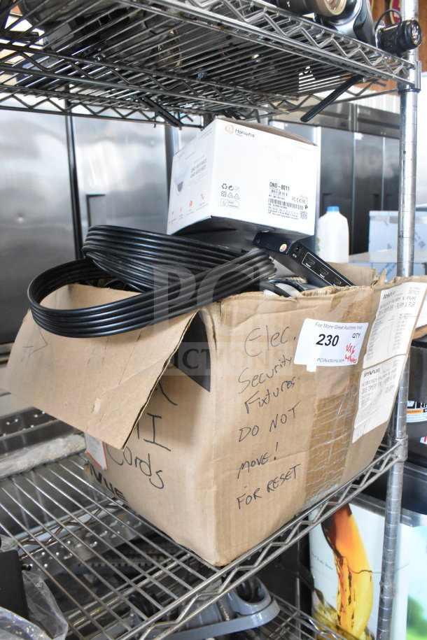 Box with HDMI splitter, cables, and electronics on a metal rack. Includes handwritten notes and warehouse labels.