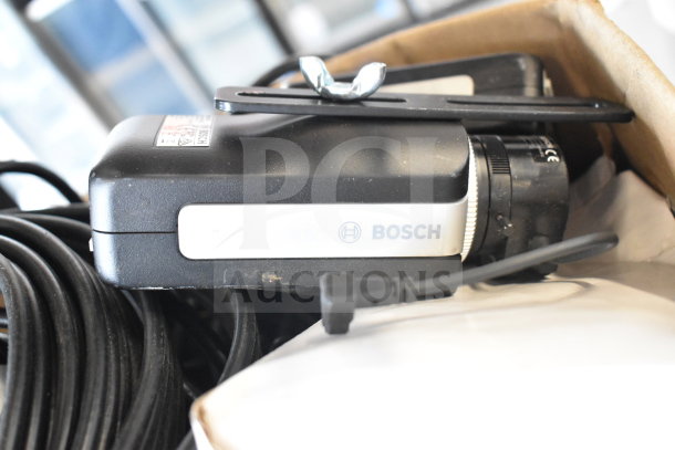 Box of various items including Bosch camera, HDMI splitter, and cables. Items have visible wear, boxed for auction.