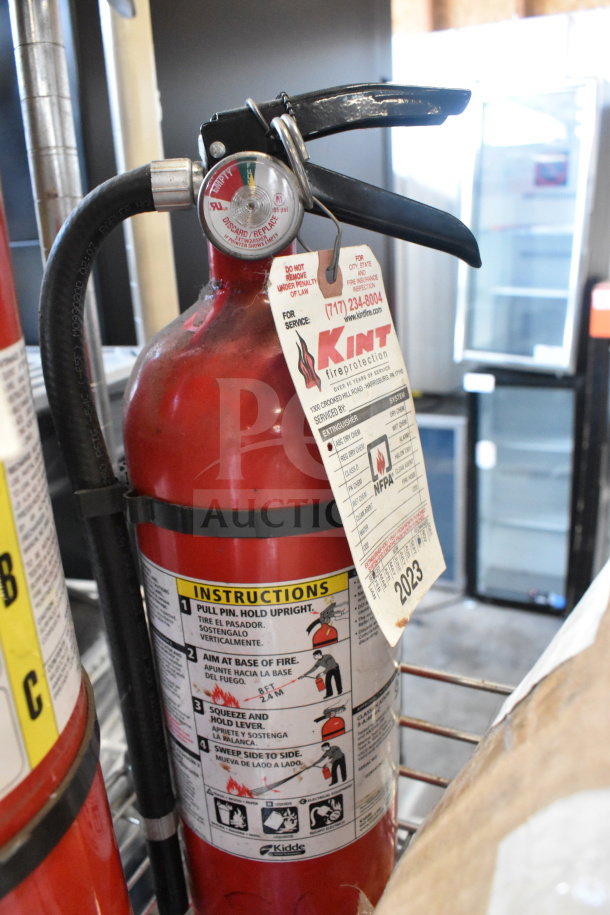 Two red fire extinguishers, including an Amerex model. Includes inspection tag from Kint Fire Protection. Buyer pickup required.