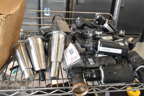16 Bosch cameras and metal legs, mixed lot, visible tags with lot number 233, on metal shelf.