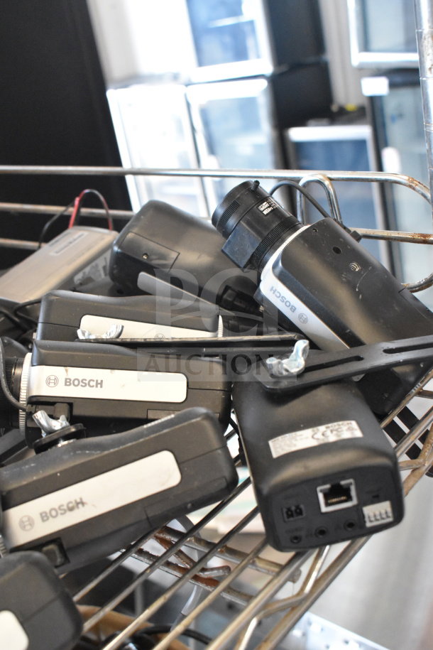 Bosch cameras assortment in metal rack, visible logos and ports, auction lot of 16 various items.
