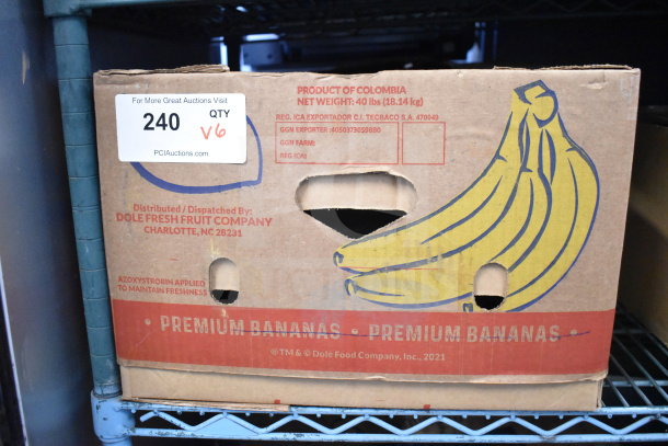 Cardboard box labeled "Premium Bananas" from Dole, marked for auction with lot number 240, containing various items.