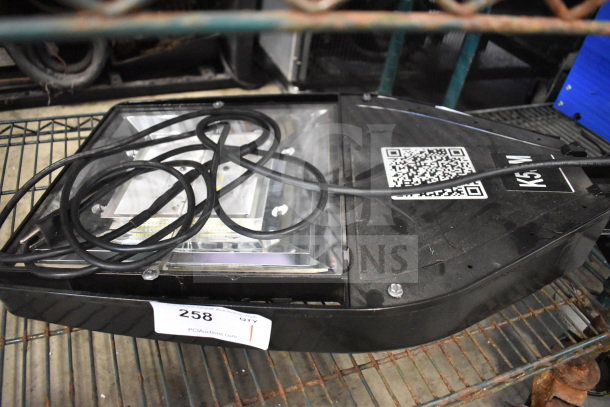 Square black light fixture with transparent cover, visible wiring, and QR code label. Auction tag reads "258".