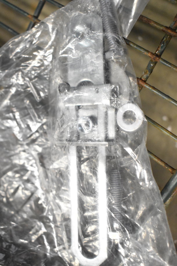 Clear plastic-wrapped metal assembly piece with bolts, part of a lot including a shorting cap and Bosch manual, auction item.