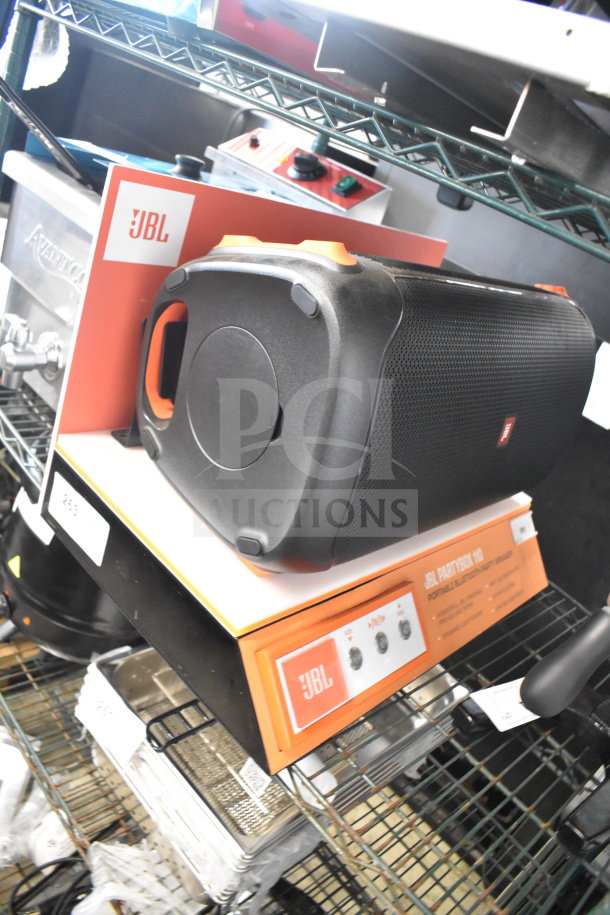 JBL Partybox 110 speaker on store display shelf. Black, portable, with JBL logo. Includes original packaging.