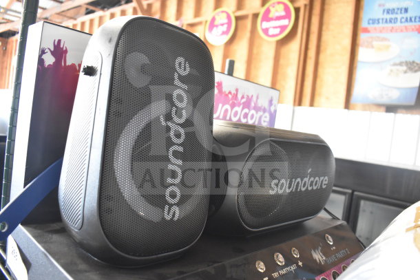 Soundcore store display featuring two black speakers with brand logo, in good condition, showcasing audio functionality.