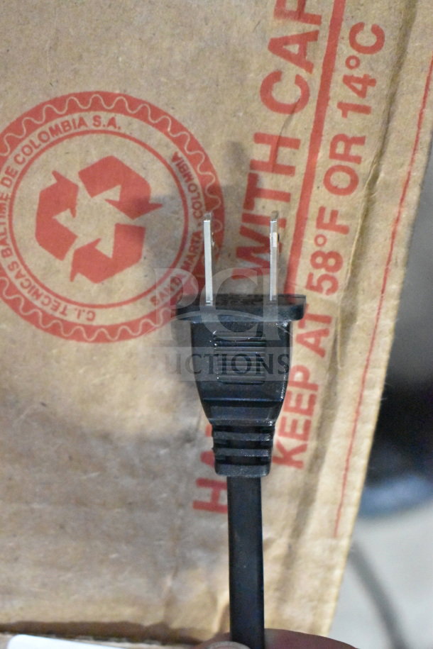 Power plug against a cardboard box with recycling logo and temperature warning, part of Onn Large Party Speaker display.