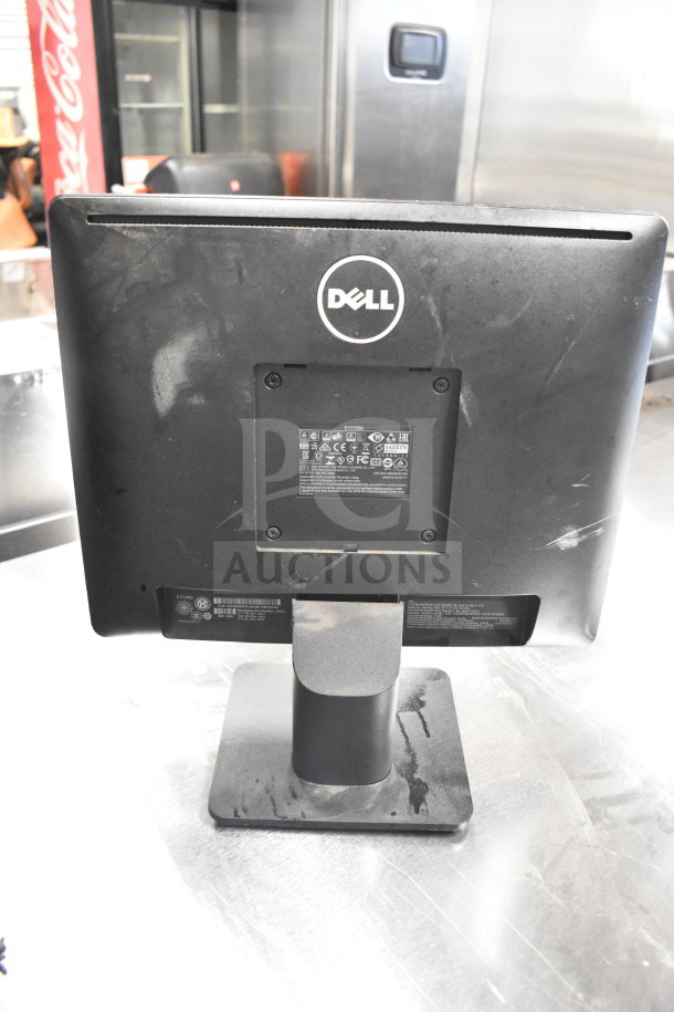 Rear view of a black Dell computer monitor on a stand, visible labels showing model information. Monitors include Dell and HP, total of six up for auction, each multiplying your bid sixfold. Dust and scuffs visible.