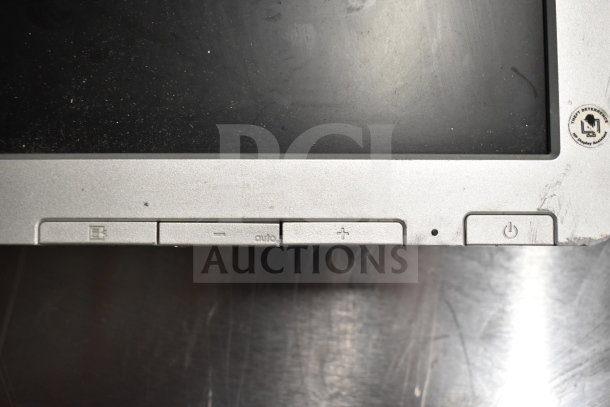 Close-up of a computer monitor's lower bezel with buttons, including power and menu. Visible label: "Thrift Determined." Slight wear.