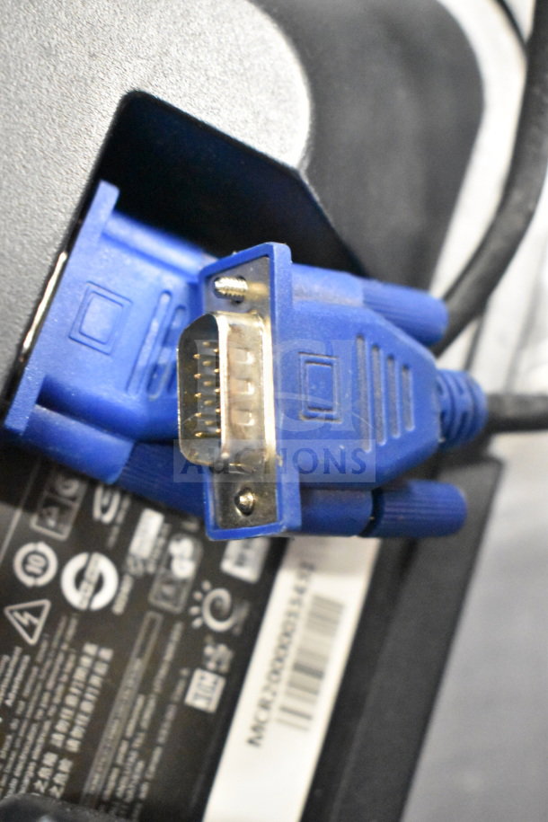 Image showing a close-up of a blue VGA connector plugged into a monitor with part of a label displaying certification marks and model numbers.