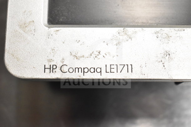 Close-up of an HP Compaq LE1711 monitor corner with visible surface wear. Part of a lot including Dell and HP monitors.