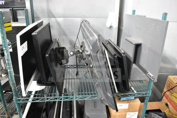 Eight monitors on a shelf, brands include Toshiba, HP, and Onn; various conditions. Tags indicate auction lot details.
