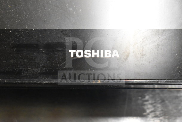 Toshiba monitor with visible logo, showing signs of wear. Part of an auction lot with 8 various monitors including HP and Onn.