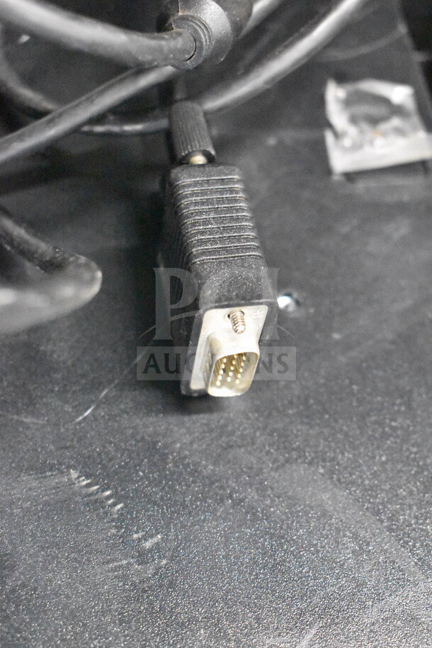 Alt text: Close-up of VGA cable connector against a black surface, part of 8 various monitors including Toshiba, HP, Onn.