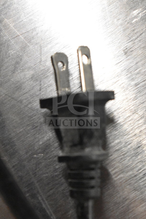 Close-up of a two-prong power plug on a stainless steel surface.