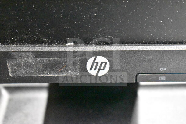 Eight monitors with brands including Toshiba, HP, and Onn. Visible HP logo, dusty surface, condition suggests used.