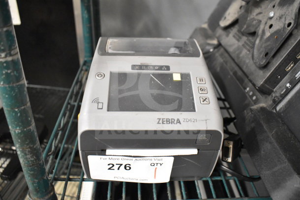Zebra ZD621 desktop direct thermal barcode printer on shelf, showing control panel. Label with auction info attached. Used condition.