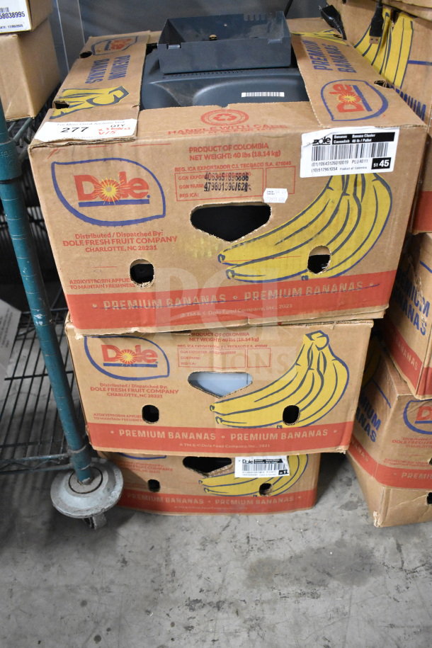 Stack of boxes labeled "Dole Premium Bananas" containing Toshiba monitors, corded office telephone, and receipt printers.
