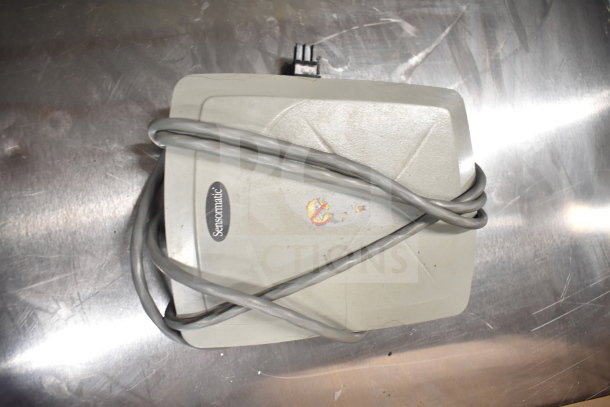 Gray Sensormatic electronic device with attached cable, showing slight wear. Part of a lot including monitors and office equipment.