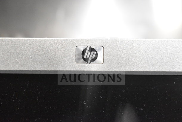 Close-up of HP monitor logo; part of a lot including Toshiba monitors, office phone, and receipt printers.