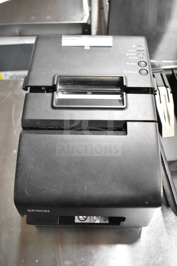 Epson receipt printer, black, with visible paper and feed buttons. Condition appears used.
