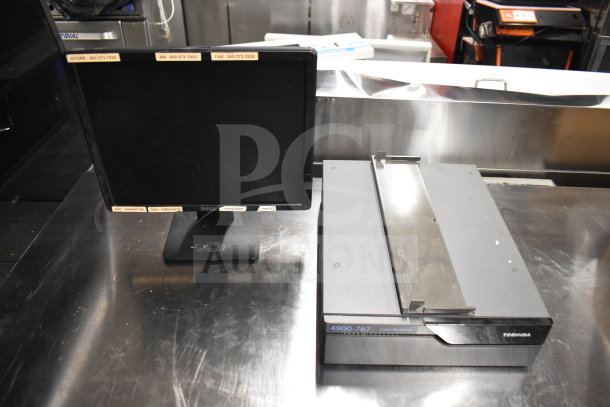 Dell monitor and Toshiba logic terminal on stainless steel surface, part of auction set; details on monitor include utility labels.