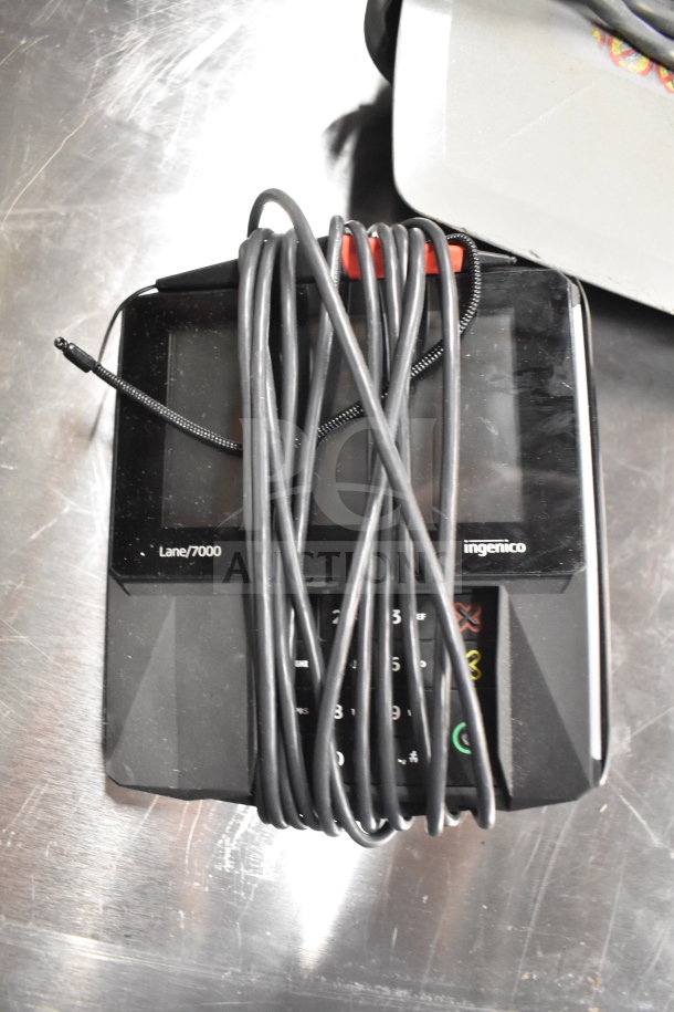 Ingenico Lane/7000 credit card reader with attached cord, part of a lot including Dell computer towers and office phones.