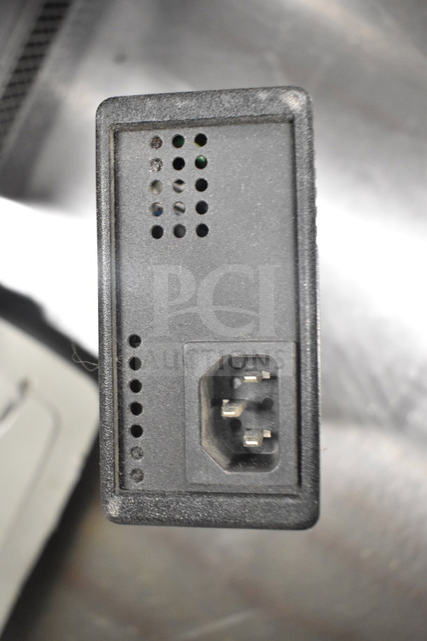 Close-up of a black electronic interface, possibly a port on a Dell computer tower, showing a connection socket and vent holes.