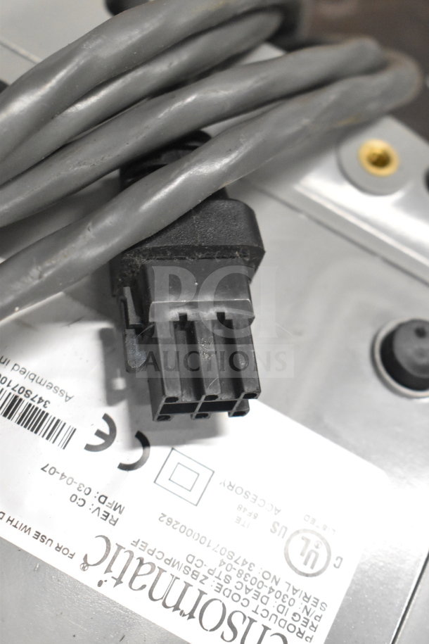 Close-up of a gray cable with a black connector, resting on a Cisco label displaying serial and model numbers.